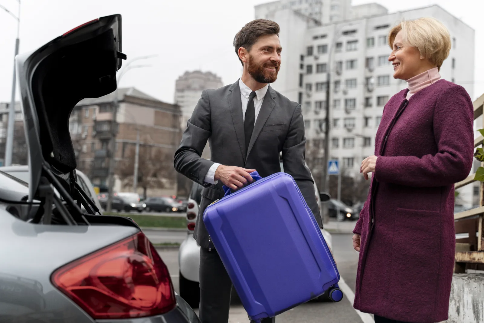 Kierowca pakuje walizkę pasażerki do bagażnika